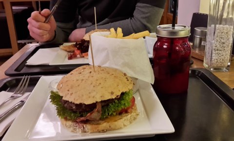 Burger und Limonade in einem roten Gefäß, auf schwarzem Tablett.